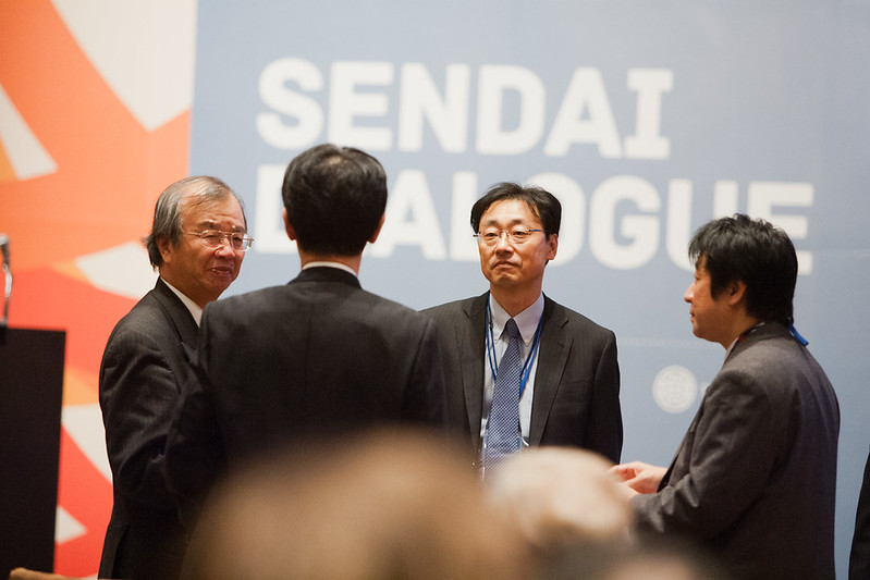 Delegates in conversation in front of the Sendai Dialogue banner